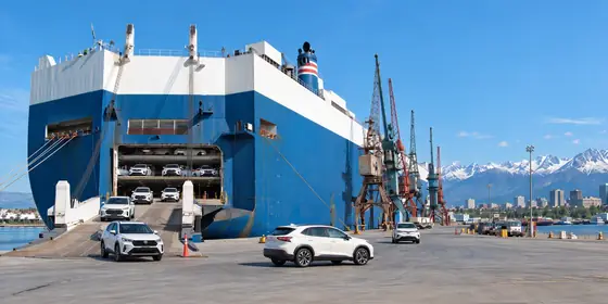 A car ship at port with Alaska mountains behind