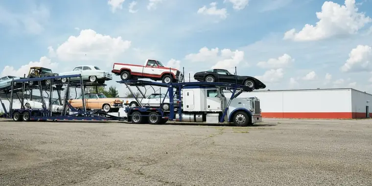 Classic cars and a vintage pickup on an open car carrier