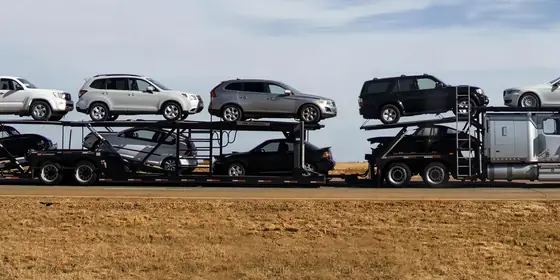 A car carrier loaded with pickups and SUVs crossing open country
