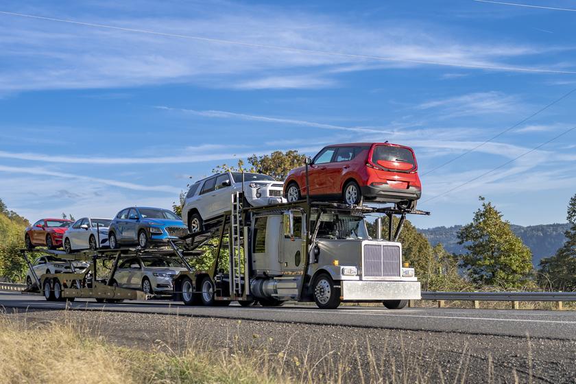 An open two-level auto transport carrier loaded with everyday cars on the highway