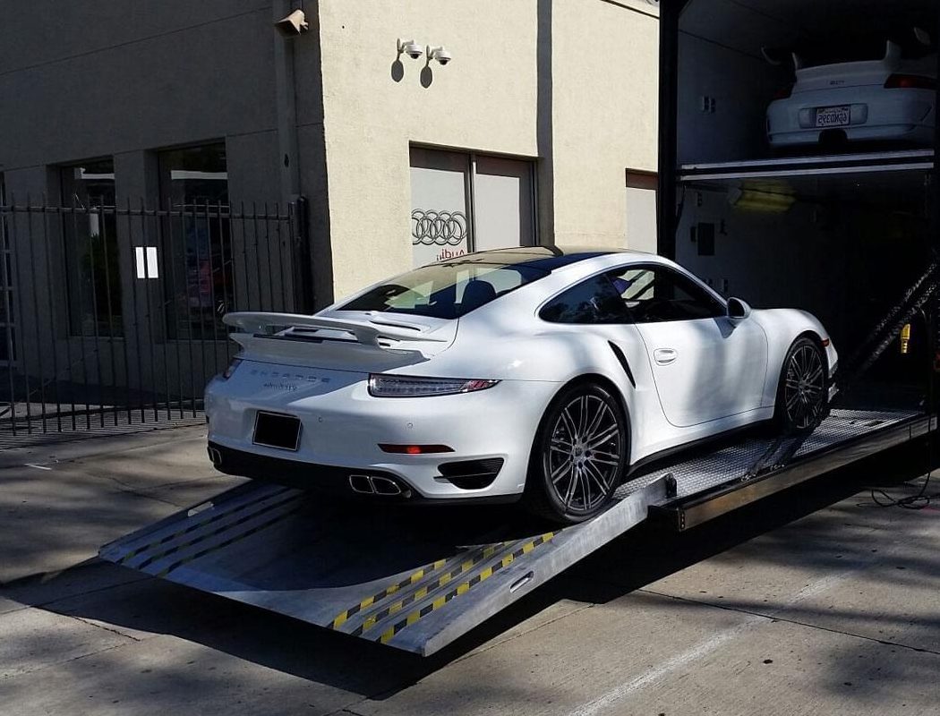 Sports car loading up the ramp into a hard-sided enclosed auto transport trailer