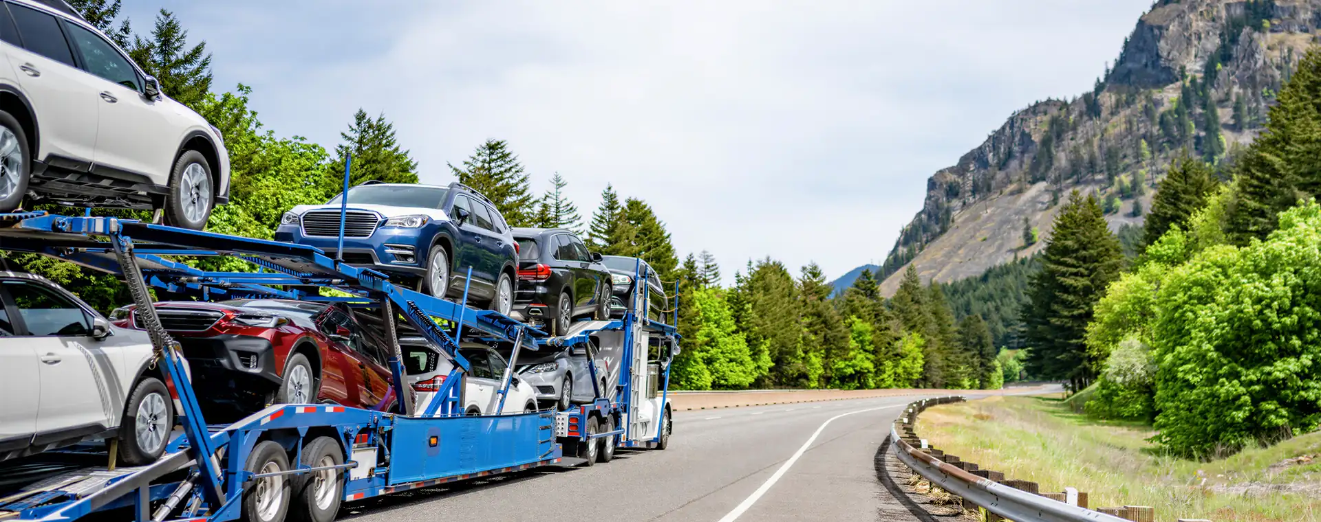 Open car transport: a loaded open two-level car carrier on a mountain highway