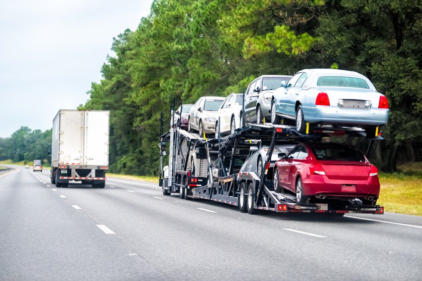 A loaded open car carrier on a summer highway during moving season
